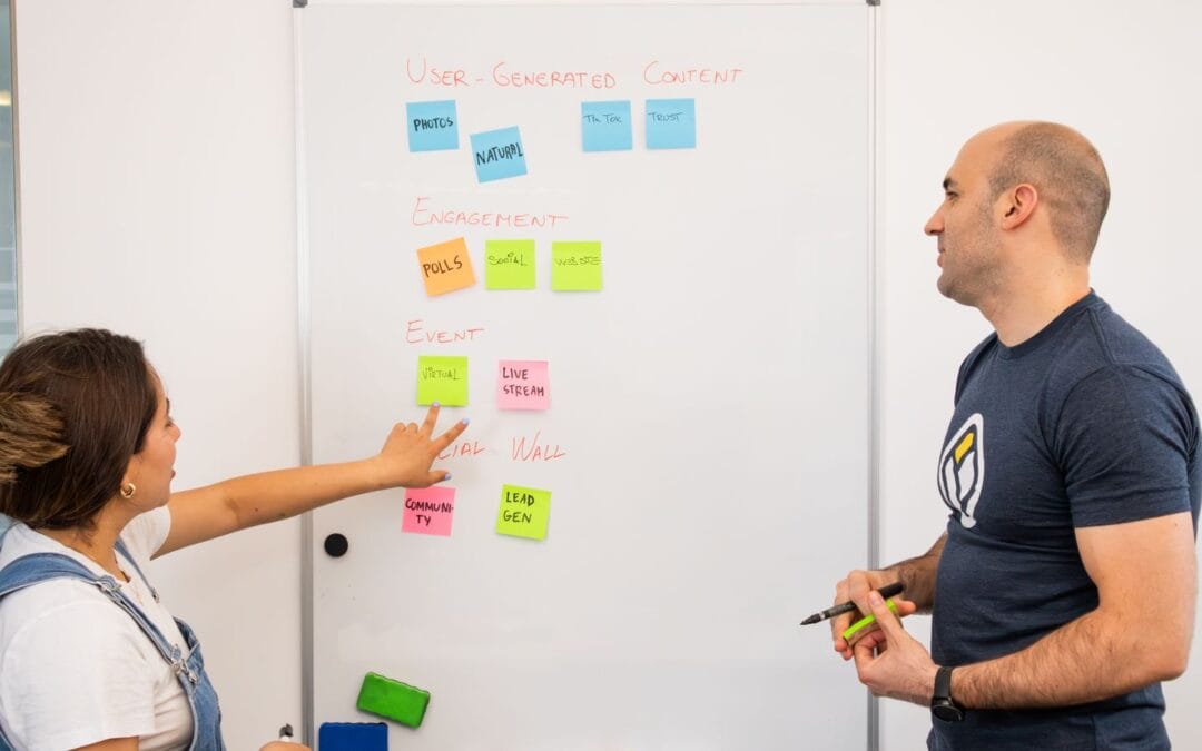 Three colleagues comparing notes at a whiteboard while planning an SEO, AEO and GEO strategy